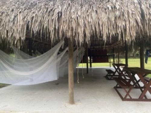 a straw umbrella with a table and chairs under it at Camping Tequendama - Parque Tayrona in El Zaino