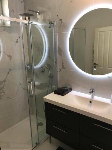 une salle de bain avec une douche, un lavabo et un miroir dans l'établissement LAZARE Maison de Maître , appartements de standing avec parking privatif à seulement 7 minutes à pied du centre historique de Béziers, à Béziers