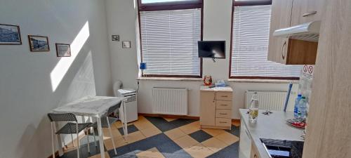 a room with a kitchen with a table and windows at Nowy Apartament Słoneczny in Augustów