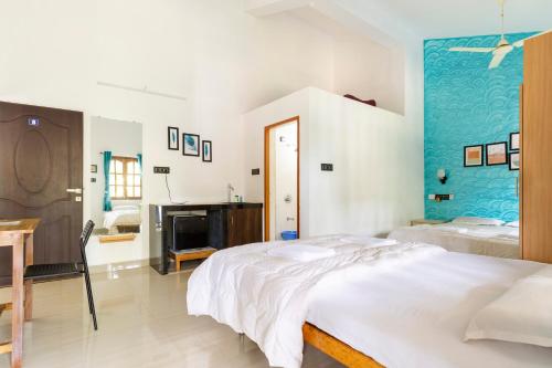 a bedroom with a white bed and a blue wall at Casa De Mor Villa with Pool in Anjuna