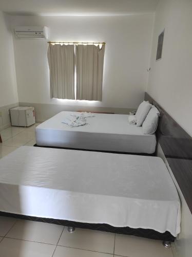 two beds in a small room with a window at Pousada Sol Nascente in Piranhas