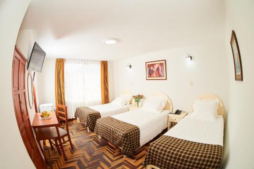 Cette chambre comprend 2 lits et une table. dans l'établissement Astorga Hotel Arequipa, à Arequipa