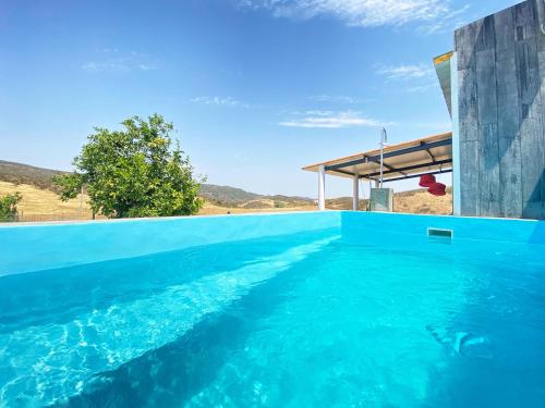 a swimming pool with blue water in a house at Casa dos chocalhos-Piscina-Perto Praia Fluvial-Vista incrível e sossego in Mértola