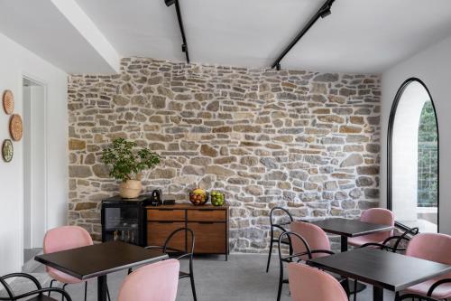 a room with tables and chairs and a stone wall at Bridges Residence in Veliko Tŭrnovo