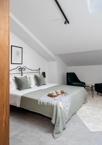 a bedroom with a bed and a green chair at Bridges Residence in Veliko Tŭrnovo