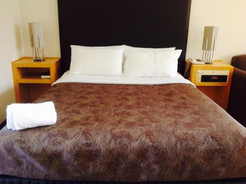 a bedroom with a large bed with two night stands at Sandown Regency Hotel & Apartments in Noble Park
