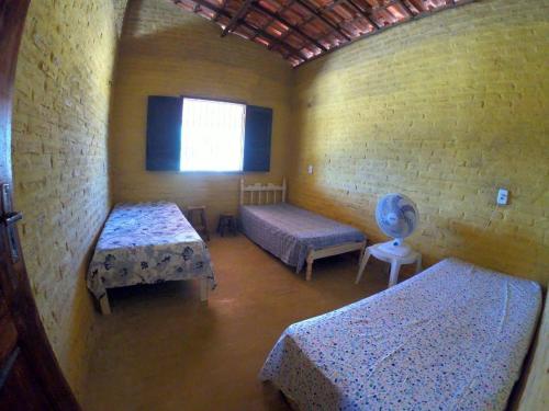 a small room with two beds and a window at Pires House Beach Maramar in Luis Correia