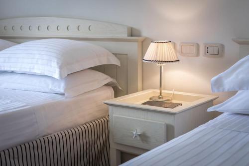 a bedroom with two beds and a table with a lamp at Murè Hotel Numana in Numana