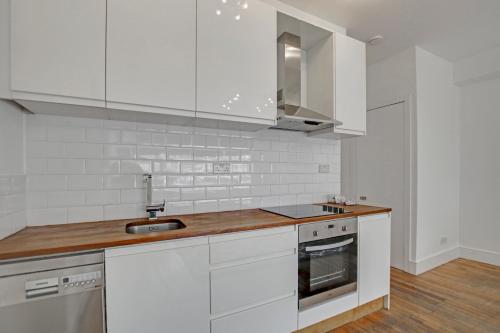 eine Küche mit weißen Schränken und einer hölzernen Arbeitsplatte in der Unterkunft 331 in London