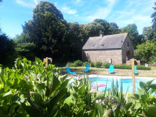 an old barn and a swimming pool in front of a house at Gîte La Grange in Langoëlan