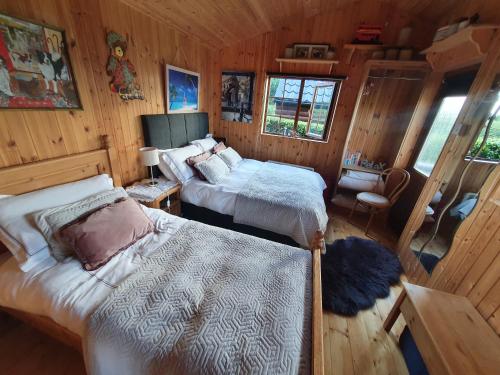 Cosy Countryside Log Cabin في كيلكيني: غرفة نوم بسريرين في كابينة خشبية