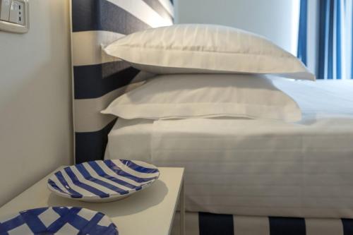 a bed with white pillows and a bowl on a table at Murè Hotel Numana in Numana