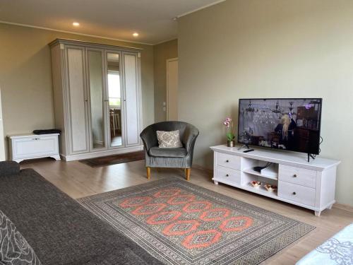 uma sala de estar com uma televisão de ecrã plano e uma cadeira em Merevaatega kesklinna korter em Haapsalu