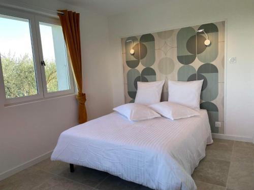 a bedroom with a bed with white sheets and a window at Gîte Les Muguets - 4 personnes - confort et vue imprenable in Largentière