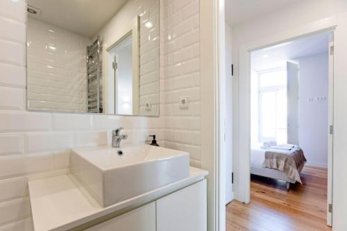 uma casa de banho branca com um lavatório e um espelho em Stunning Duplex Near River by LovelyStay no Porto