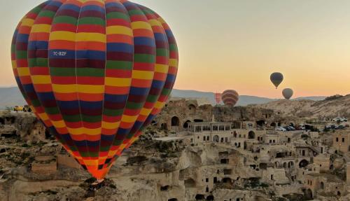 um grupo de balões de ar quente sobrevoando um castelo em Fairyland Cave Hotel em Goreme