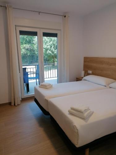 two beds in a hotel room with a balcony at Villa El Encinar de Noja in Noja