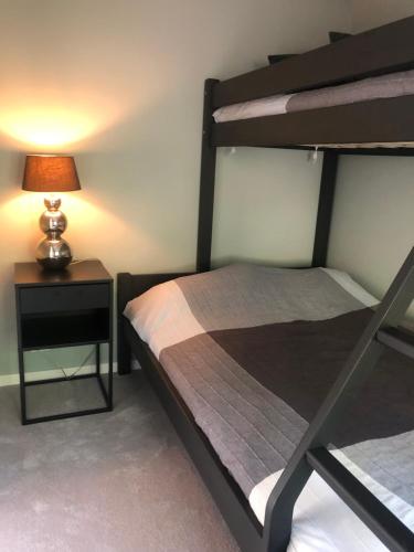 a bedroom with a bunk bed and a nightstand with a lamp at Strandhytte in Kristiansand