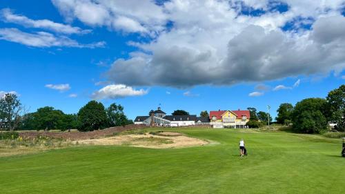 um homem de pé num campo de golfe com uma casa ao fundo em Holiday Apartment Köpingsvik em Köpingsvik