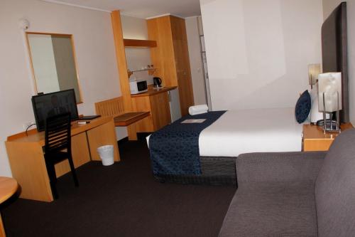 a small hotel room with a bed and a desk at Sandown Regency Hotel & Apartments in Noble Park