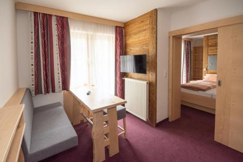 a hotel room with a desk and a bedroom at Embacherhof in Embach
