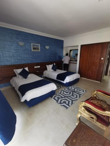 a hotel room with two beds and a man in the background at Hôtel Des Iles in Essaouira