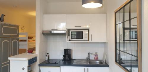 une cuisine blanche avec un évier et un micro-ondes dans l'établissement Studio dans résidence avec piscine et parking, à La Couarde-sur-Mer