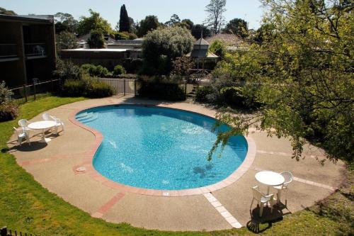 a swimming pool with two tables and two chairs around it at Sandown Regency Hotel & Apartments in Noble Park