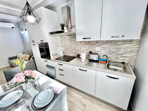 uma cozinha com armários brancos, um lavatório e uma mesa em Accogliente appartamento a due passi dalla metro em Moncalieri