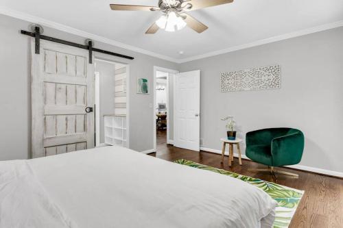 a bedroom with a white bed and a green chair at Lakefront, Saltwater Pool, Backyard Oasis, Private Dock, Home Gym in Flowery Branch