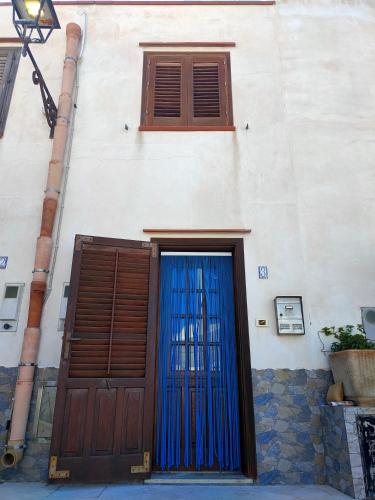 a building with two doors with blue gates at Marettimo la casa sulla spiaggia in Marettimo