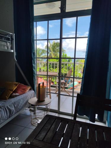 1 dormitorio con ventana grande con vistas a la piscina en STUDIO PIEDS DANS L EAU A SCHOELCHER, en Schœlcher