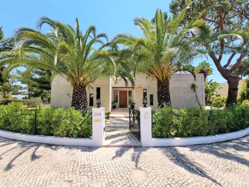 a house with palm trees in front of it at Villa Fati With Pool by Vacationy in Troia