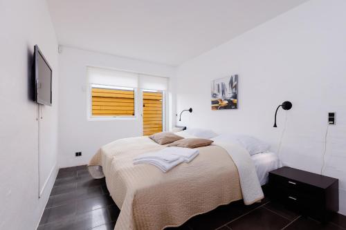 a white bedroom with a bed and a window at Eksklusiv ferielejlighed in Rudkøbing