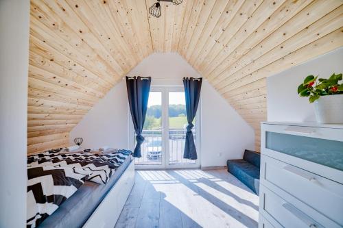 Cette chambre comprend un lit et une grande fenêtre. dans l'établissement Oaza, à Gołubie