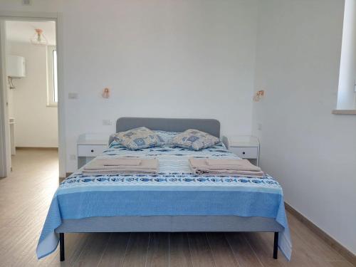een bed in een witte kamer met een blauwe deken bij La terrazza di Elena in Fasano
