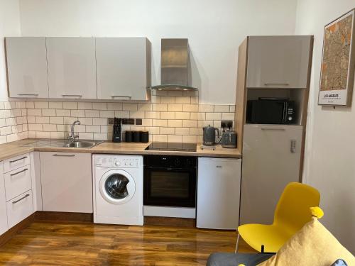 a kitchen with white appliances and a yellow chair at Cosy Apartment in the Heart of Leicester in Leicester