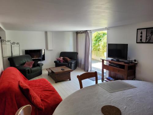 een woonkamer met een bank, een tv en een tafel bij logement à 50 m de la mer ! in Hermanville-sur-Mer