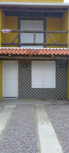 un edificio de ladrillo con tres puertas blancas de garaje. en Recanto das Pedras- Casa Pedra Ardósia - Com vista para o mar en Jaguaruna