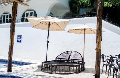 two chairs and an umbrella next to a pool at Hotel Rio Atlixco in Atlixco