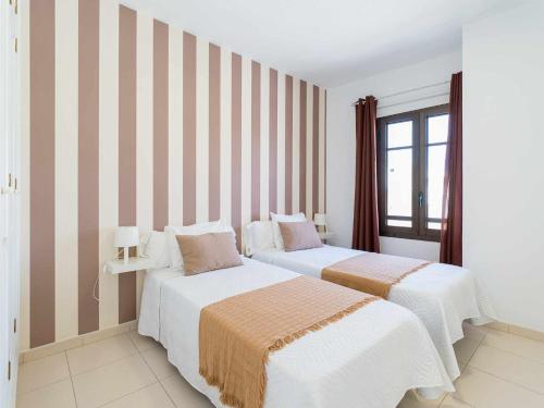 twee bedden in een kamer met gestreepte muren bij Mahostly Apartamento Comillas SB in Arrecife
