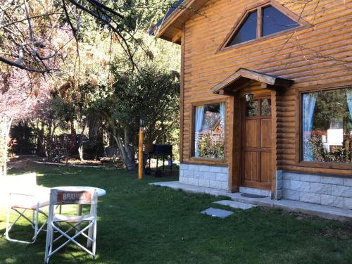 a house with a wooden door and a chair in the yard at Cabañas Villa Centauro in San Carlos de Bariloche