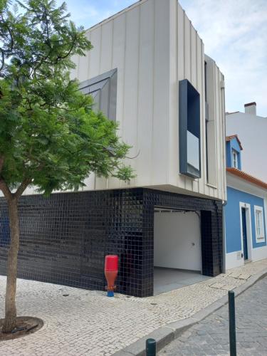 a building with a red door and a tree at Casa Aveiro Modern House in Aveiro
