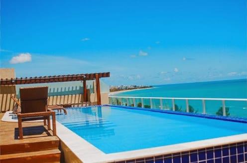 a swimming pool on top of a building with the ocean at Confortável Flat com piscina de borda infinita na cobertura in Cabedelo