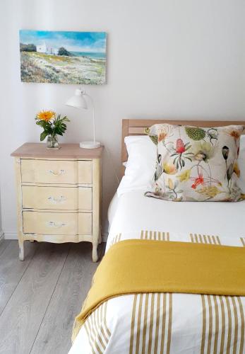 a bedroom with a bed and a nightstand with a bed sidx sidx at Hilton Cove Beach House in Melkbosstrand