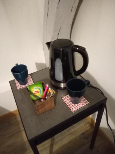 a black coffee pot sitting on a table with two cups at LE MARCEL appartement F1 de 24 m² in Choisey