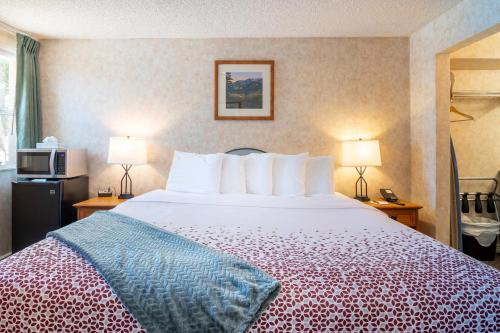 a large bed in a hotel room with two lamps at Swiss Alps Inn in Heber City