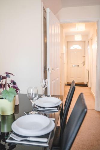 a dining room table with chairs and white plates on it at Snapos Apartments - Tudor Close in Carbrook