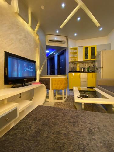 eine Küche mit gelben Schränken und einem TV auf der Theke in der Unterkunft أجمل شاليه فى بورتو مطروح للعائلات فقط in Marsa Matruh