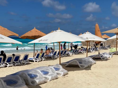 people sitting in chairs under umbrellas on a beach at أجمل شاليه فى بورتو مطروح للعائلات فقط in Marsa Matruh